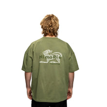 Person wearing a green t-shirt with a logo and text on the back, on a white background
