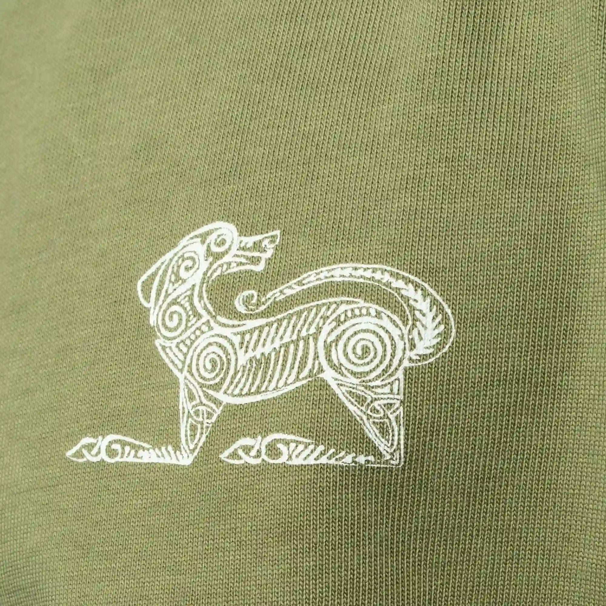 White printed design of a stylised animal on a green fabric background