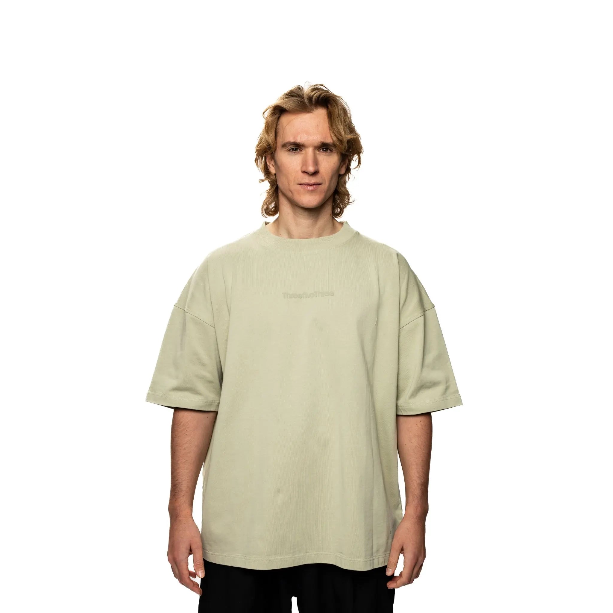 Man wearing a light green t-shirt with text on a white background