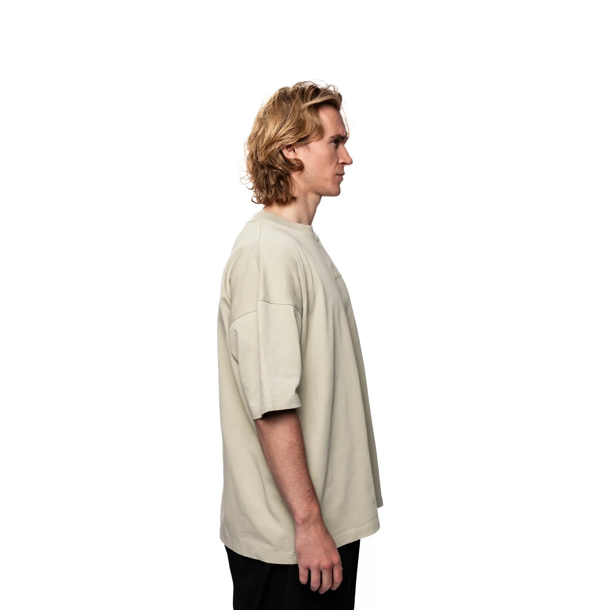 Person wearing a beige oversized t-shirt on a white background