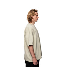 Person wearing a beige oversized t-shirt on a white background
