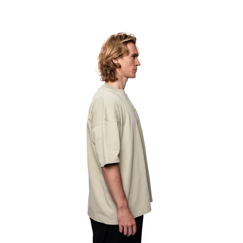 Person wearing a beige oversized t-shirt on a white background