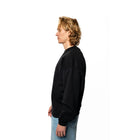 Person wearing a black sweatshirt and blue jeans on a white background